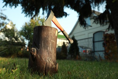 Photo of Metal axe in wooden log on backyard, low angle view