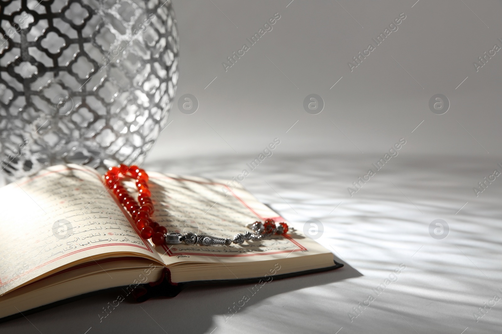 Photo of Koran with Muslim prayer beads on table. Space for text