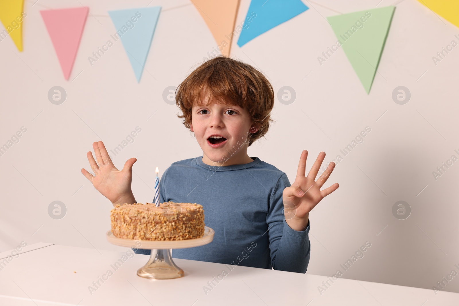 Photo of Cute boy with birthday cake at white table indoors