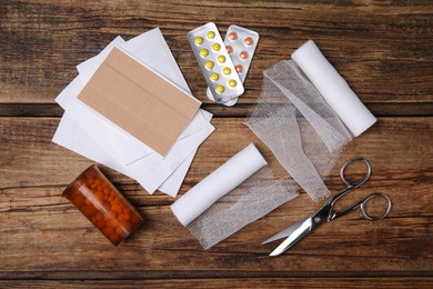 Photo of White bandage rolls and medical supplies on wooden table, flat lay