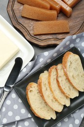 Photo of Delicious quince paste, bread, and butter on grey textured table, flat lay