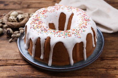 Photo of Glazed Easter cake with sprinkles on wooden table