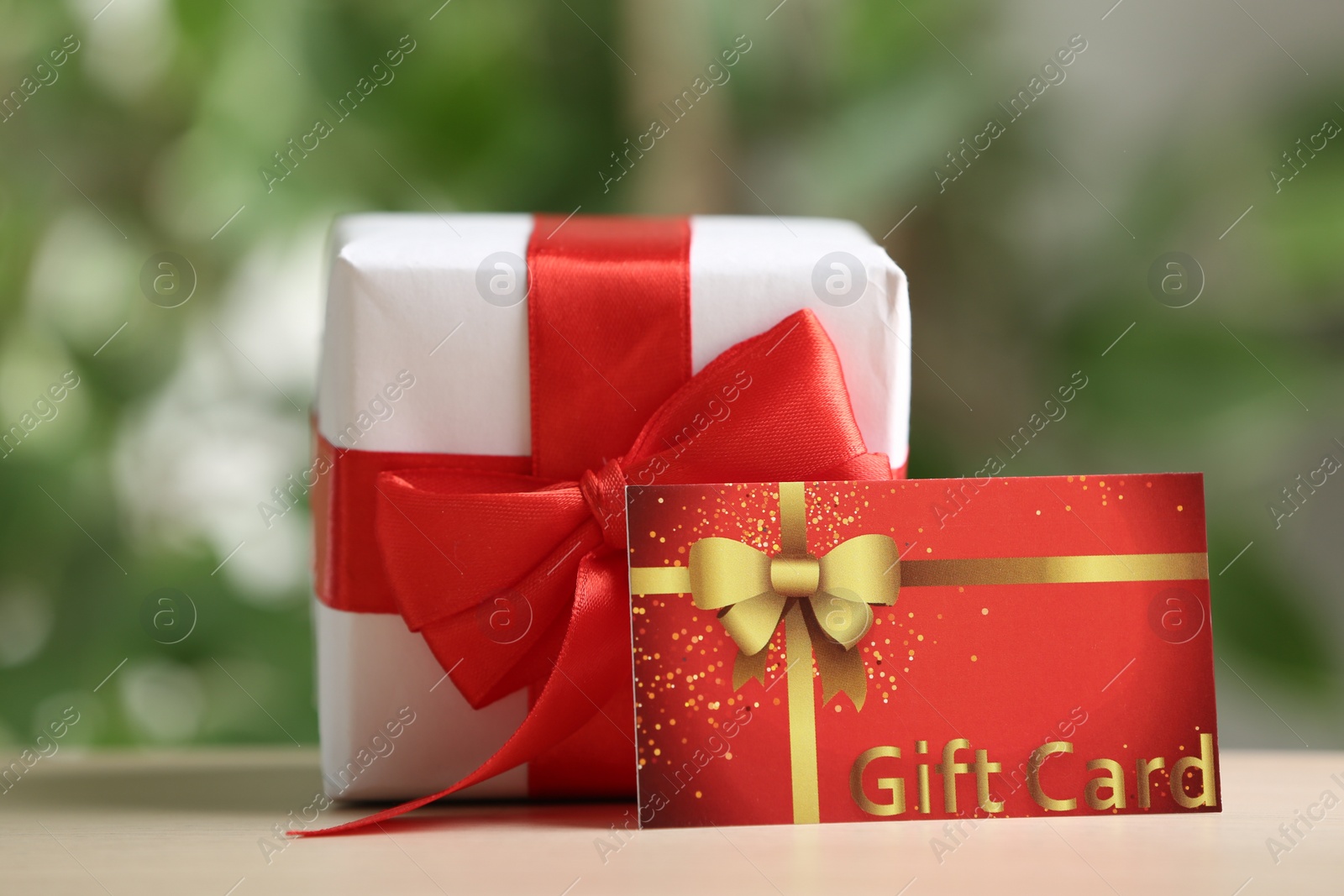 Photo of Gift card and present on table against blurred background