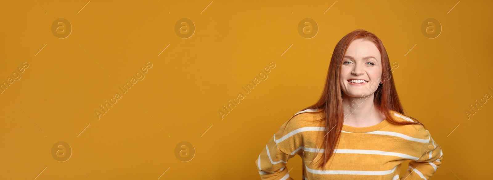 Photo of Candid portrait of happy young woman with charming smile and gorgeous red hair on yellow background