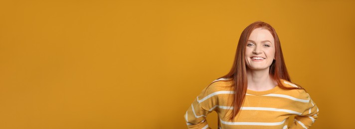 Photo of Candid portrait of happy young woman with charming smile and gorgeous red hair on yellow background