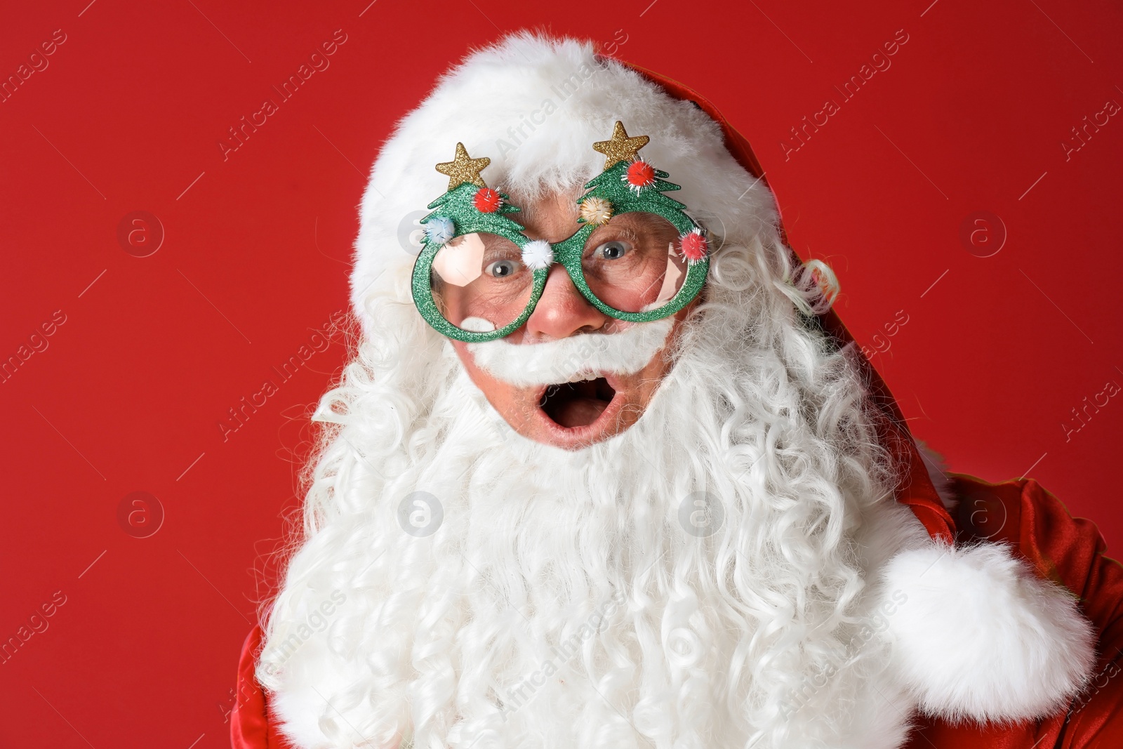 Photo of Authentic Santa Claus wearing funny glasses on color background