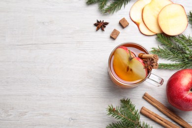 Hot mulled cider, ingredients and fir branches on white wooden table, flat lay. Space for text