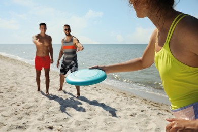 Photo of Friends playing with flying disk at beach on sunny day