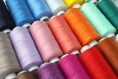 Photo of Set of different colorful sewing threads as background, closeup
