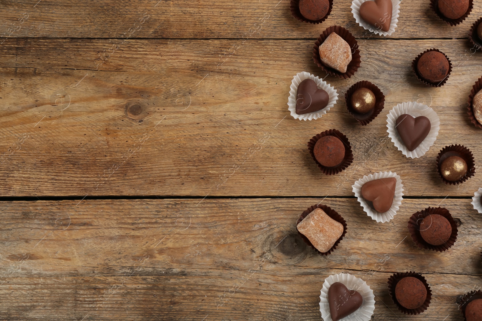 Photo of Different delicious chocolate candies on wooden table, flat lay. Space for text
