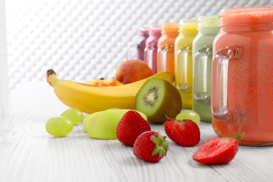 Many different tasty smoothies and ingredients on white wooden table, space for text