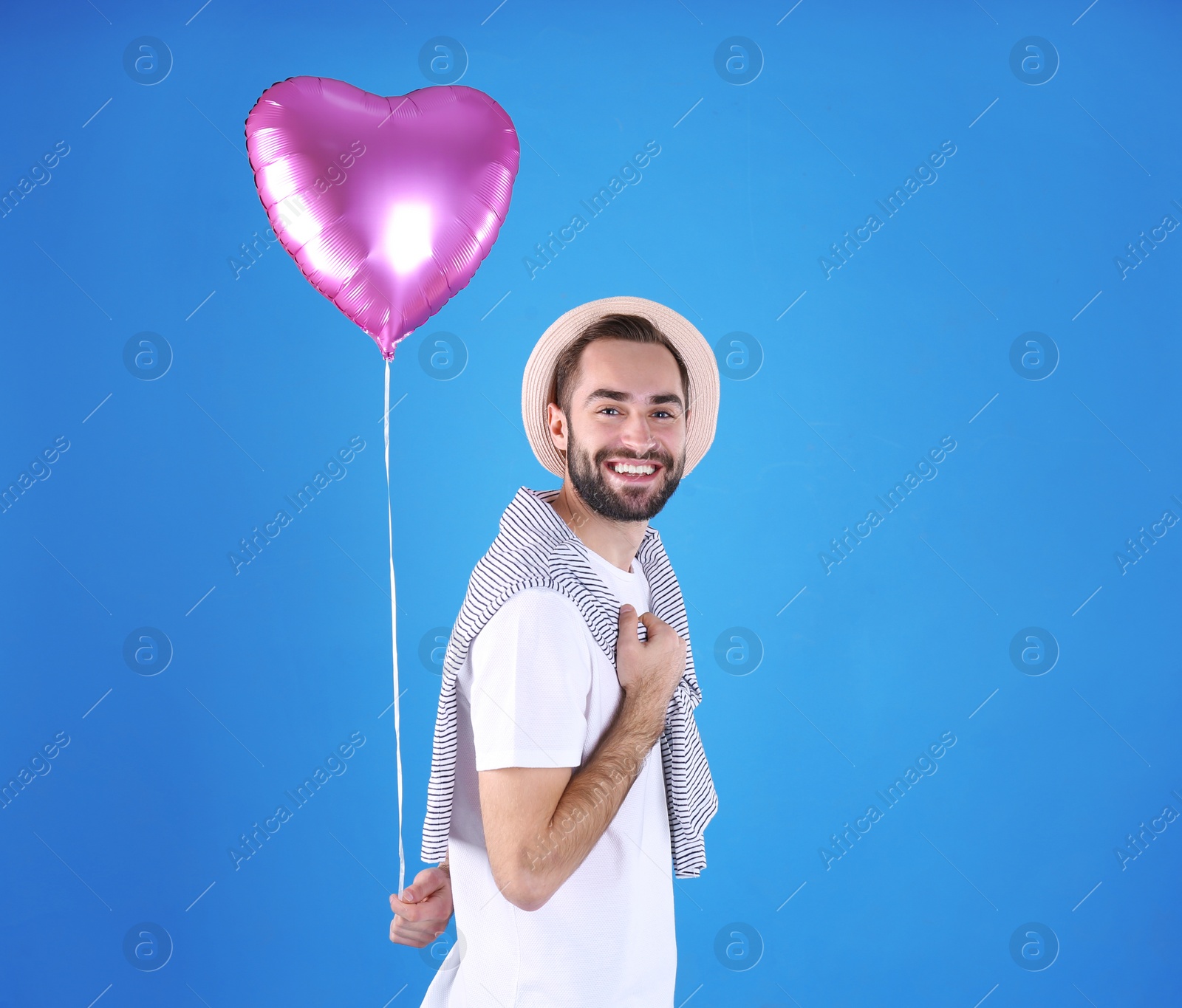 Photo of Portrait of young man with heart shaped balloon on color background