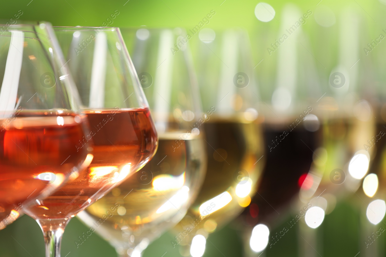 Photo of Different tasty wines in glasses against blurred background, closeup. Space for text