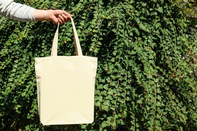 Photo of Woman holding eco bag outdoors, closeup. Mockup for design