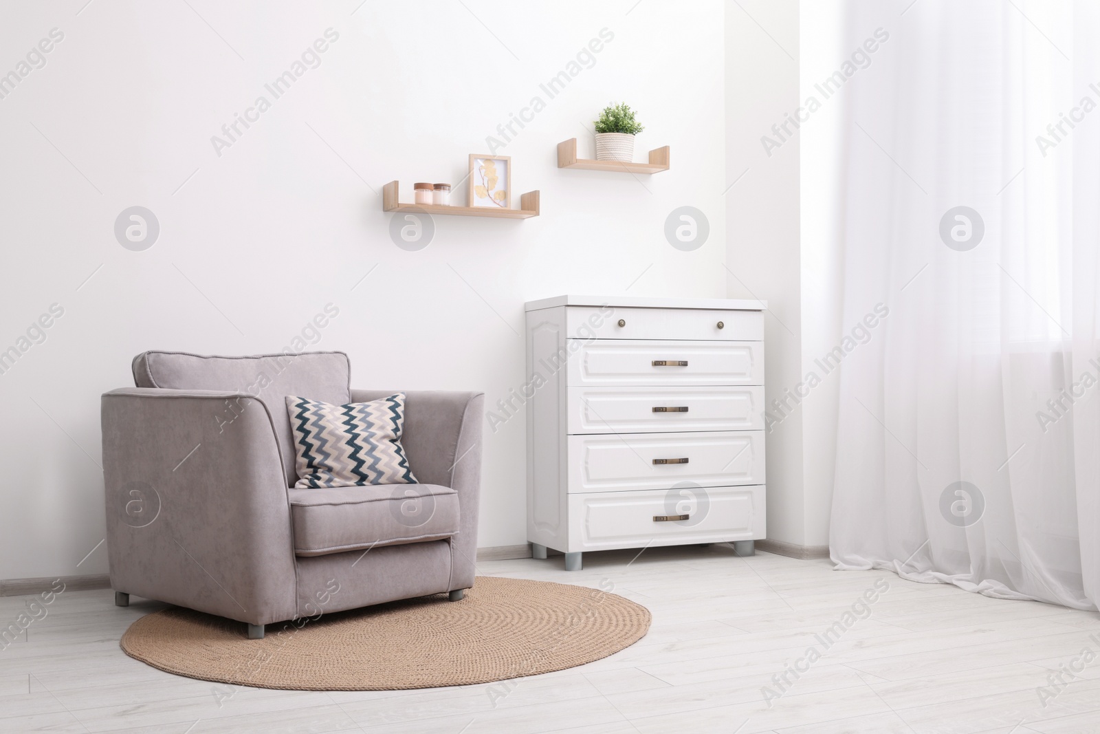 Photo of Stylish armchair and chest of drawers in room. Interior design