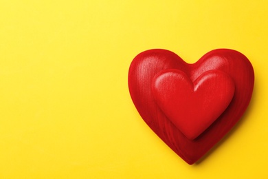Photo of Red wooden hearts on yellow background, top view. Space for text