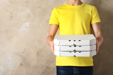 Photo of Young man with pizza boxes on color background, space for text. Food delivery service