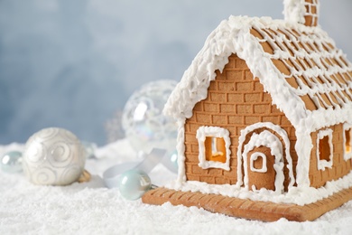 Photo of Beautiful gingerbread house decorated with icing on snow, closeup. Space for text