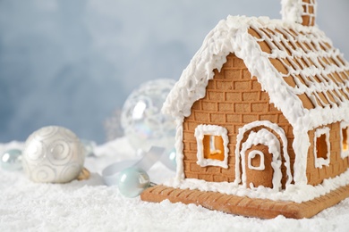 Beautiful gingerbread house decorated with icing on snow, closeup. Space for text