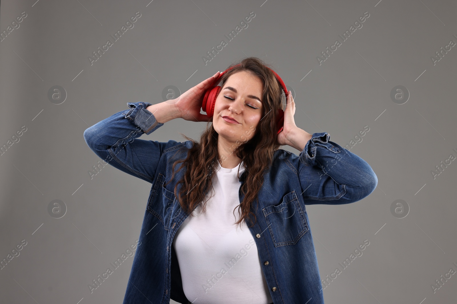 Photo of Portrait of beautiful young woman with headphones on grey background