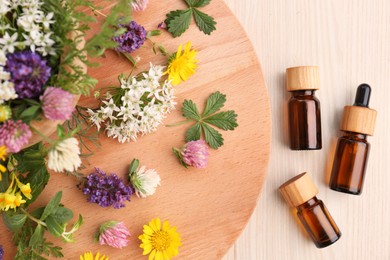 Photo of Flat lay composition with bottles of essential oil, flowers and herbs on white wooden table