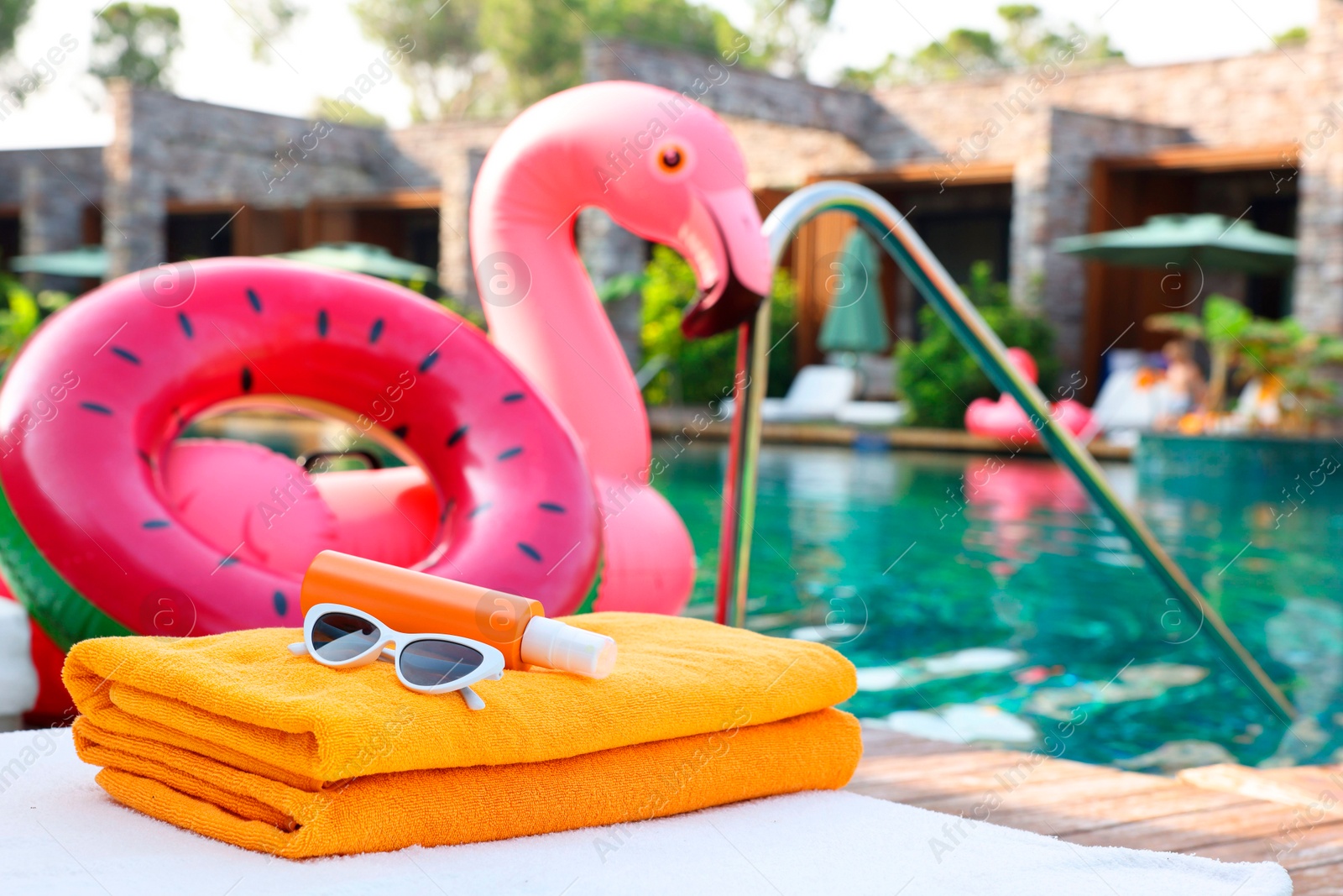 Photo of Beach accessories on sun lounger, inflatable ring and float near outdoor swimming pool at luxury resort, space for text