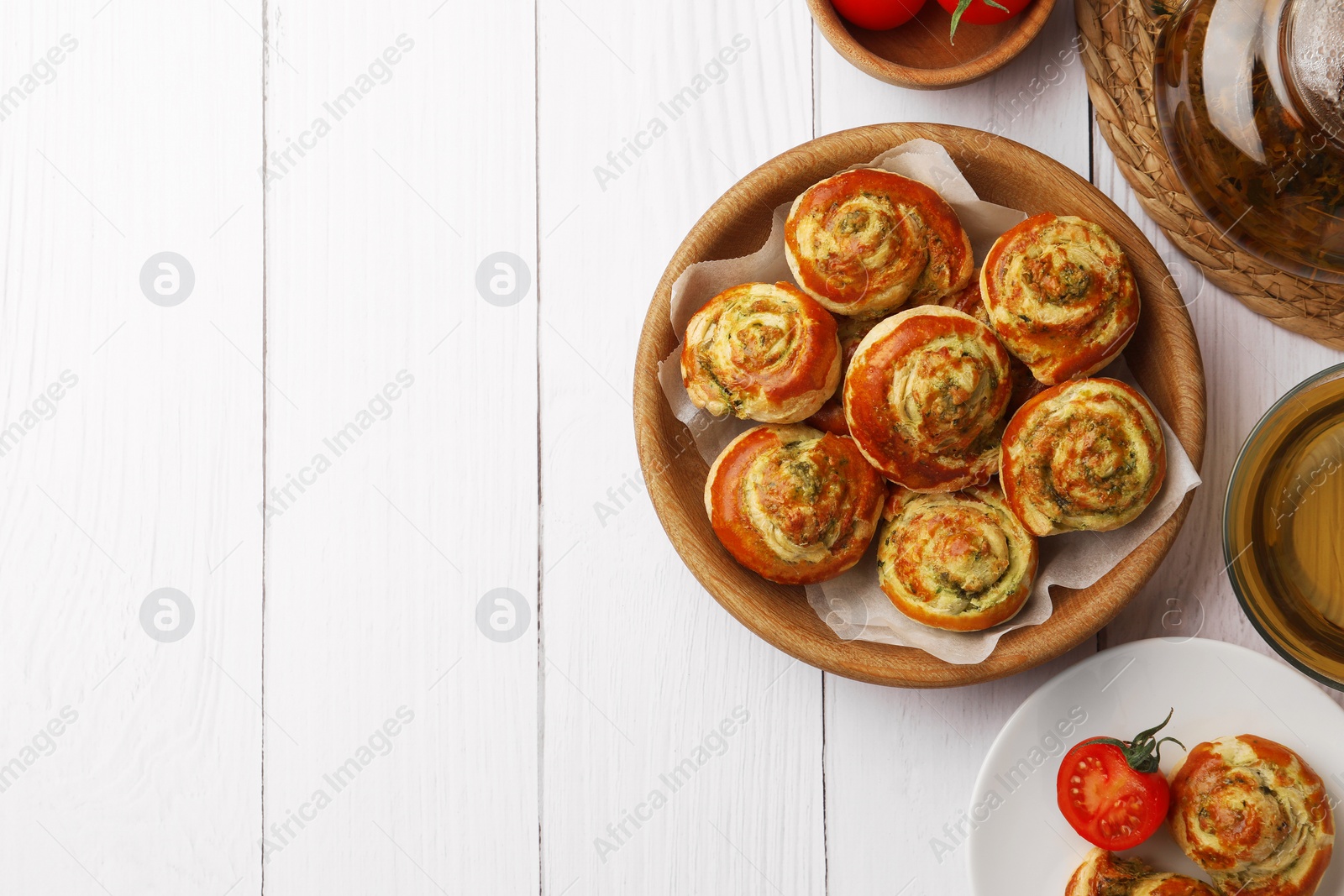 Photo of Fresh delicious puff pastry served with tea and tomatoes on white wooden table, flat lay. Space for text