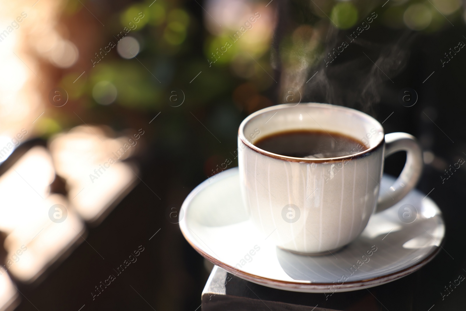 Photo of Cup of hot aromatic coffee on table in outdoor cafe. Space for text