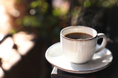 Photo of Cup of hot aromatic coffee on table in outdoor cafe. Space for text