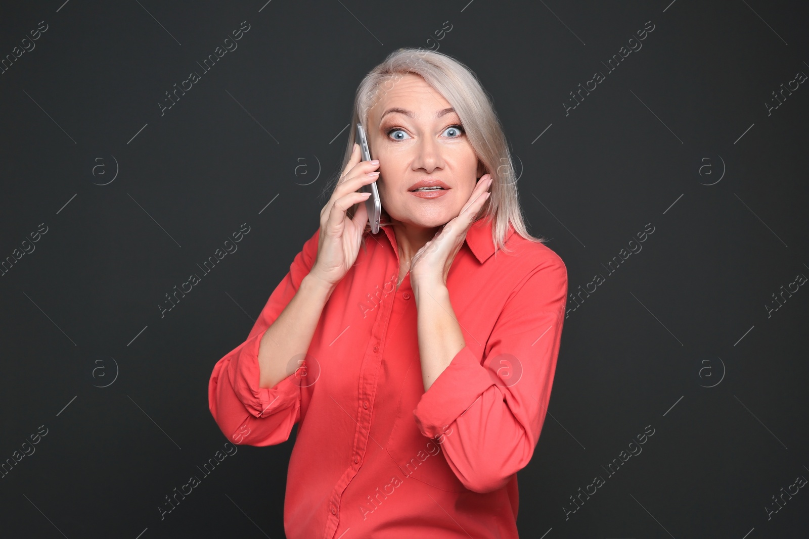 Photo of Mature woman talking on mobile phone against black background