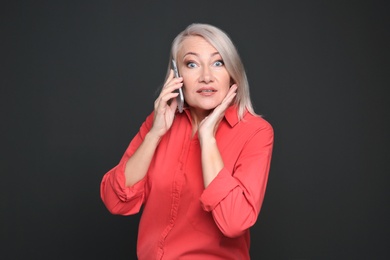 Photo of Mature woman talking on mobile phone against black background