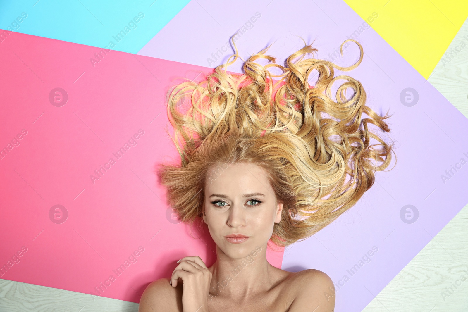 Photo of Beautiful woman with healthy long blonde hair on color background, top view