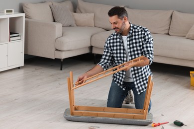 Photo of Man assembling shoe storage bench on floor at home