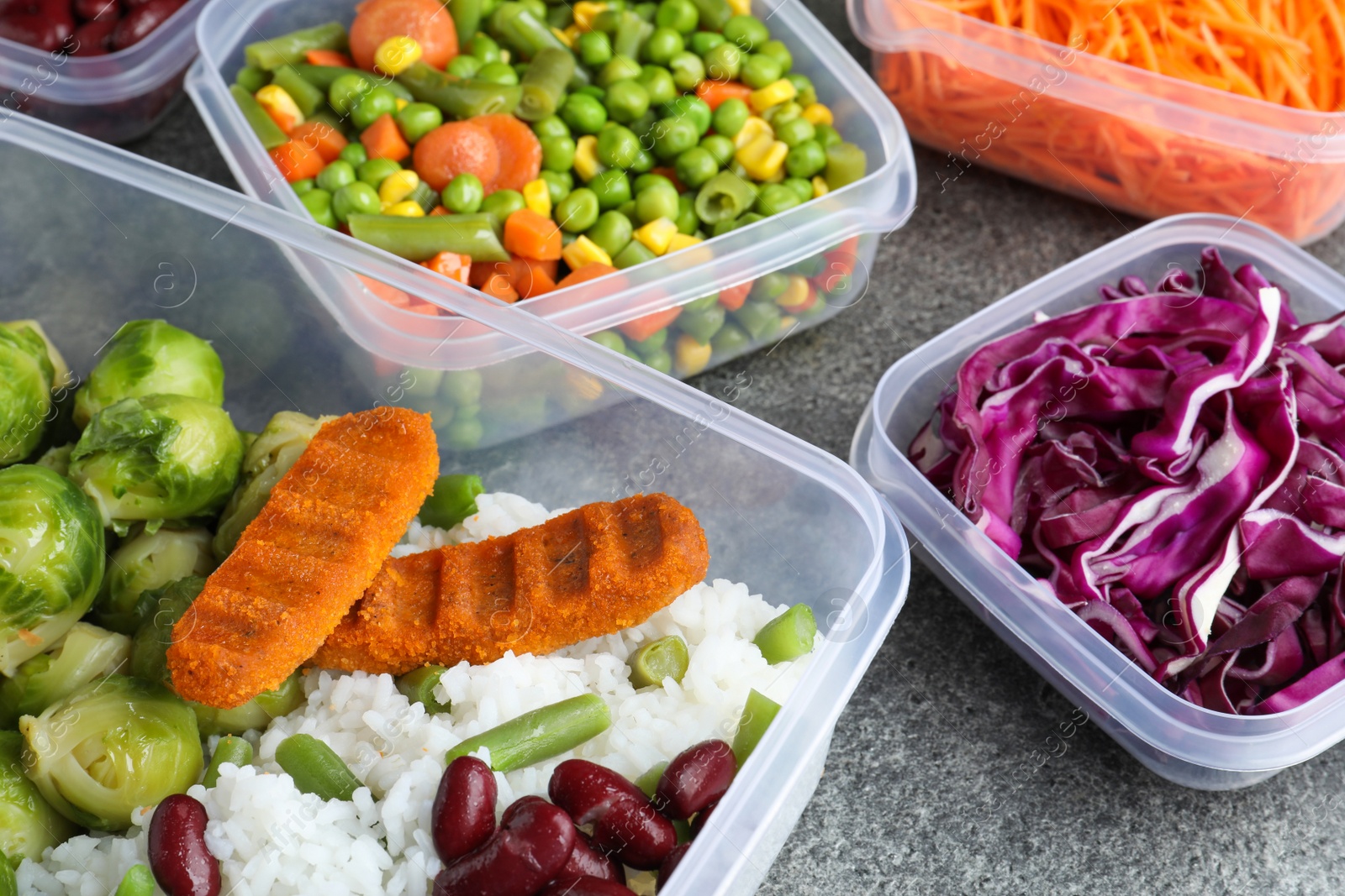 Photo of Set of plastic containers with fresh food on grey   table, closeup