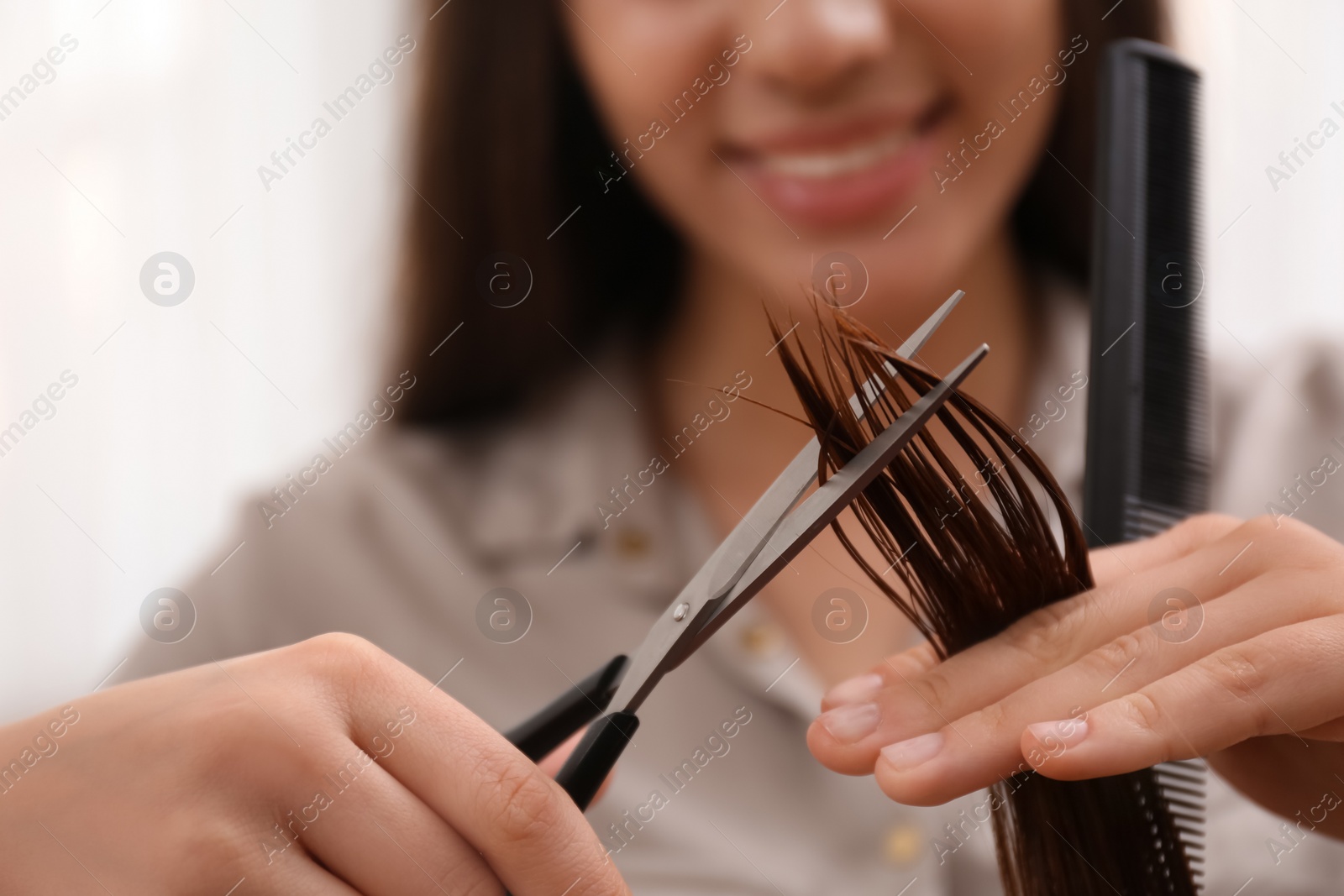 Photo of Stylist cutting hair of client in professional salon, closeup