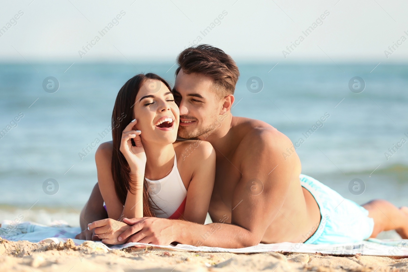 Photo of Happy young couple lying together on beach