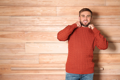 Image of Handsome man wearing warm sweater on wooden background. Space for text