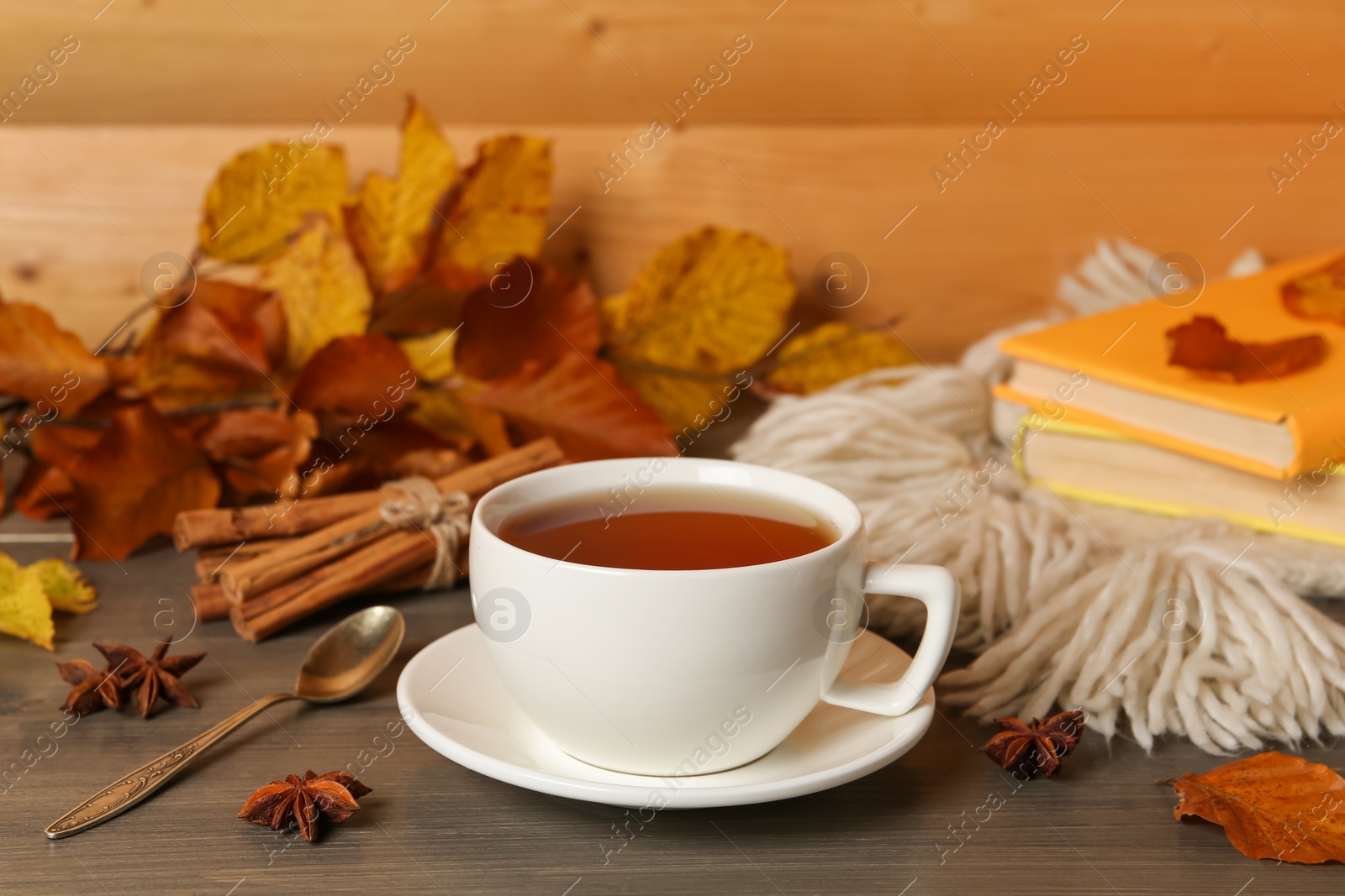 Photo of Composition with cup of hot tea and autumn leaves on wooden table