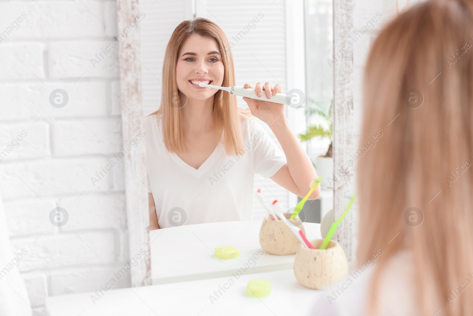 Photo of Young woman brushing her teeth in bathroom