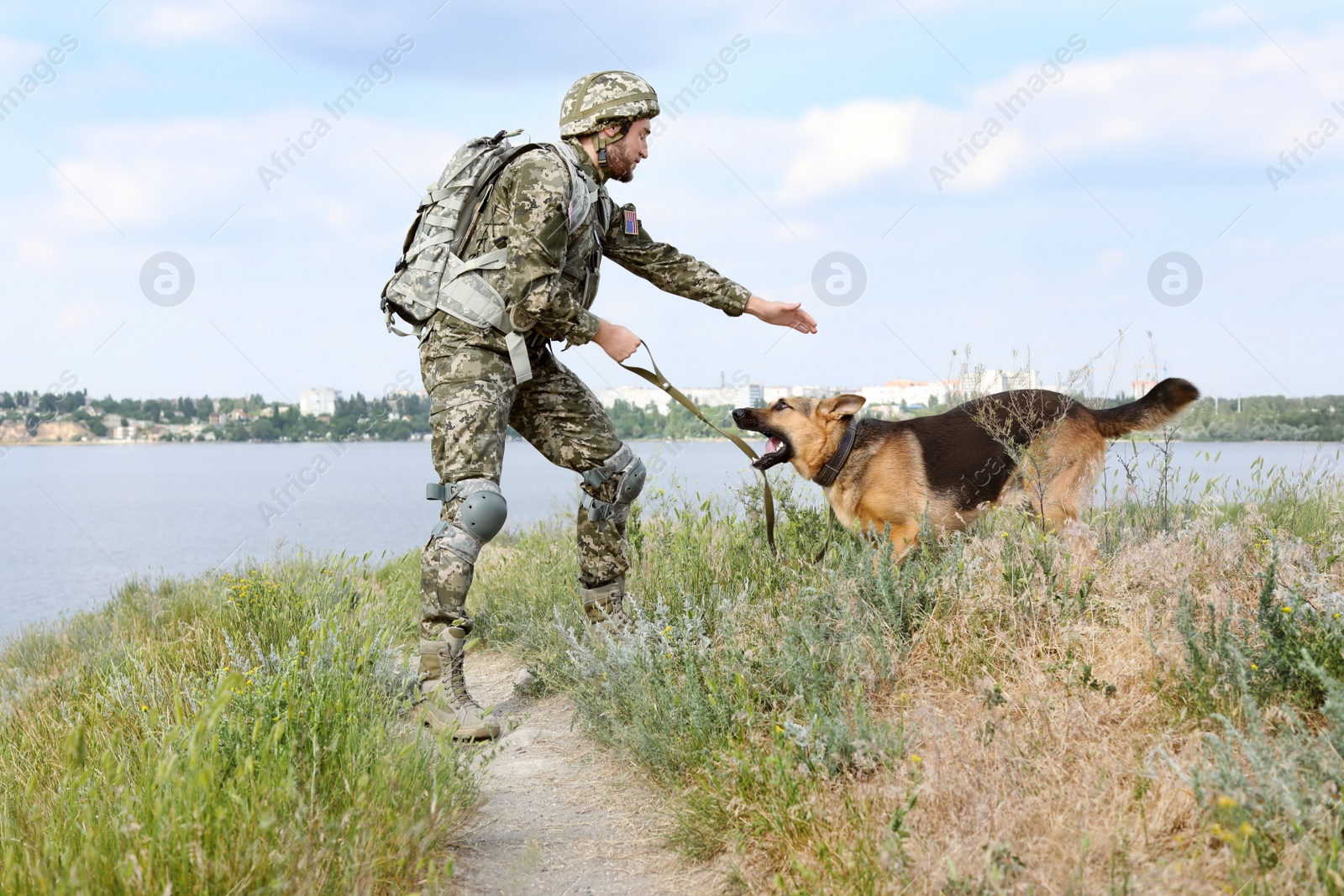 Photo of Man in military uniform with German shepherd dog outdoors