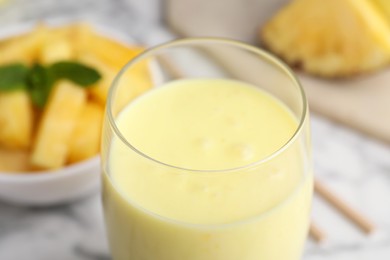 Photo of Tasty pineapple smoothie in glass on white table, closeup