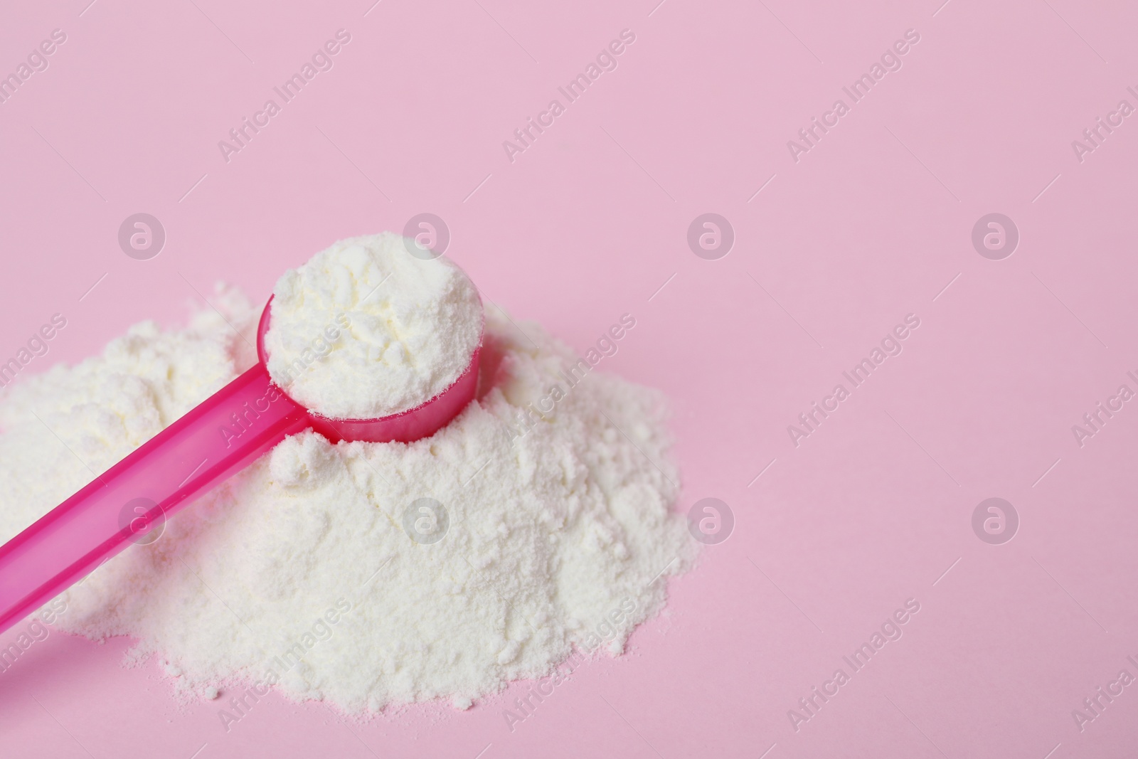 Photo of Powdered infant formula with scoop on pink background, space for text. Baby milk