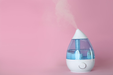 Photo of Modern air humidifier on pink background. Space for text