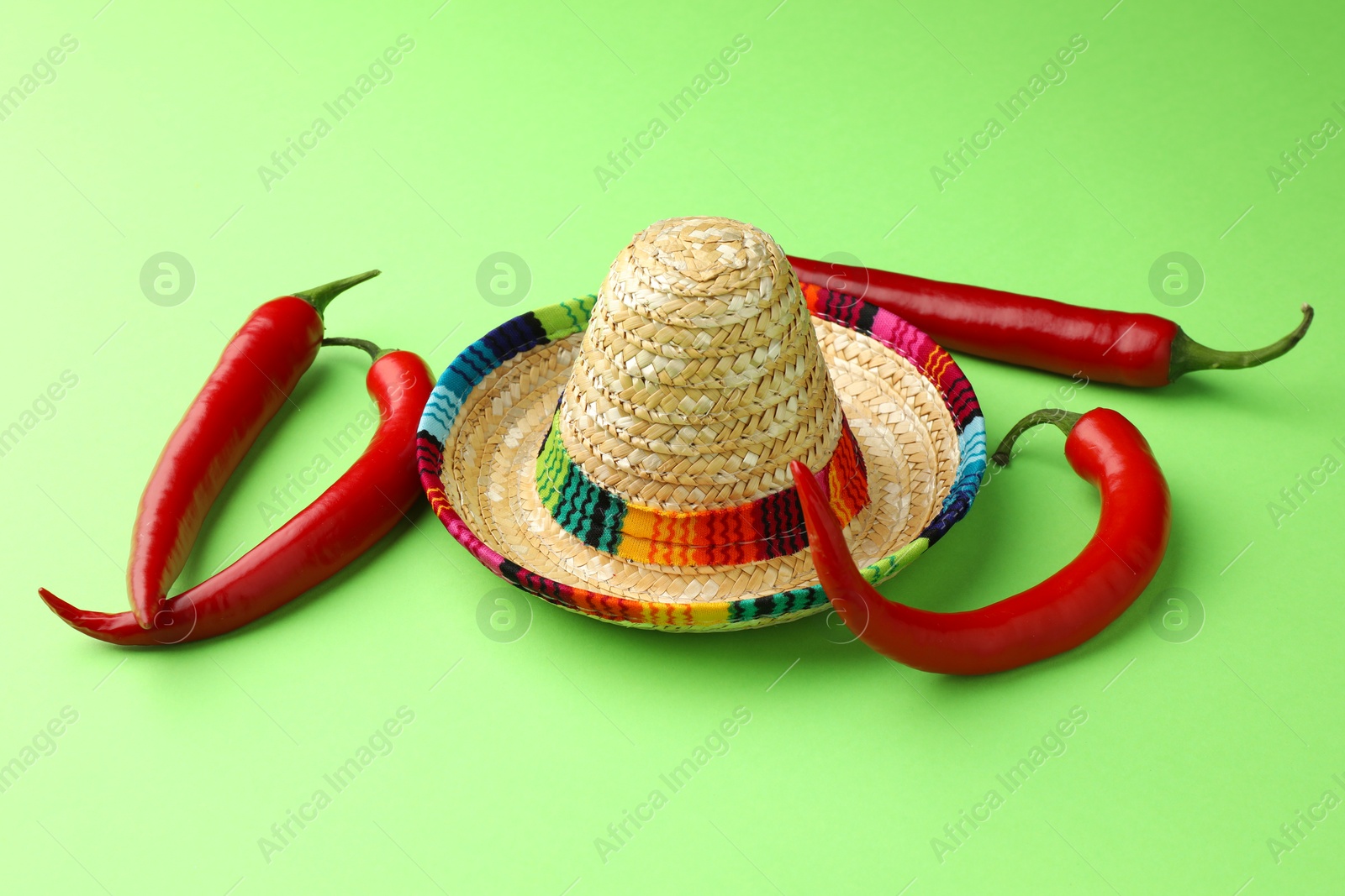 Photo of Mexican sombrero hat and chili peppers on green background