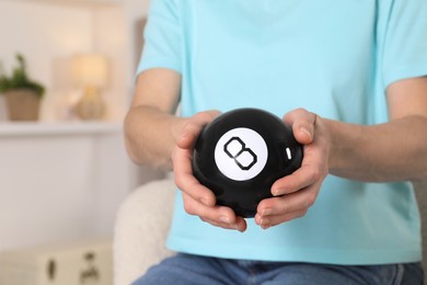 Woman holding magic eight ball indoors, closeup