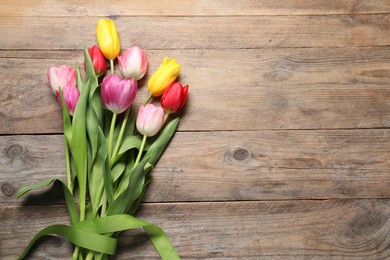 Beautiful colorful tulip flowers and ribbon on wooden table, flat lay. Space for text