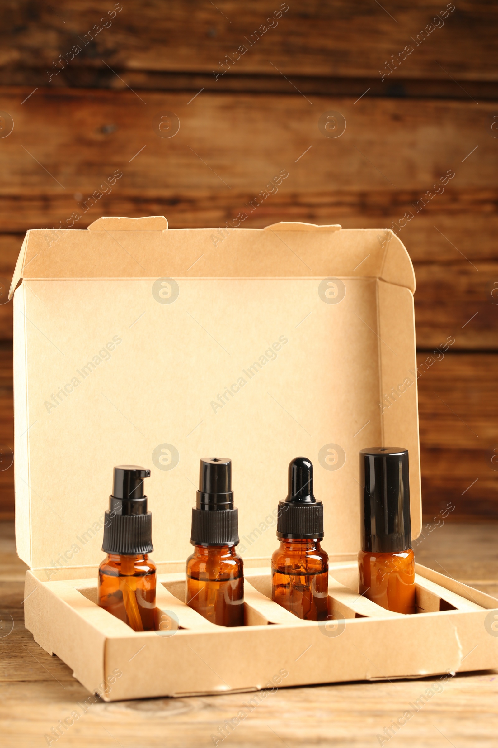 Photo of Bottles with oil in box on wooden table. Natural cosmetics