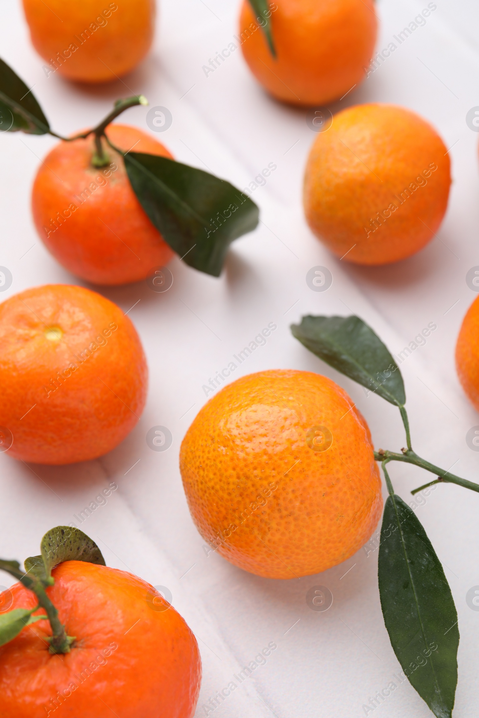 Photo of Fresh ripe tangerines with green leaves on white table