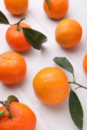 Photo of Fresh ripe tangerines with green leaves on white table