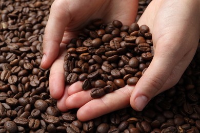 Woman with roasted coffee beans, closeup view